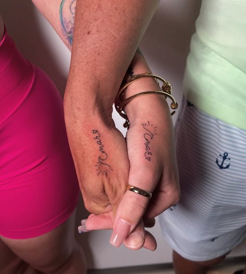 Matching delicate script tattoos with small sun on the sides of two hands