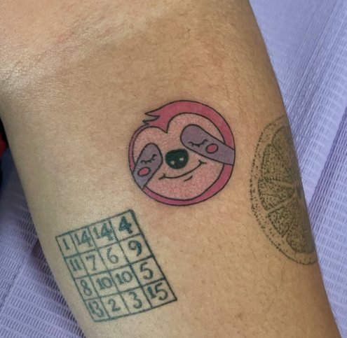 Small pink and purple sloth face tattoo, hand poked in color